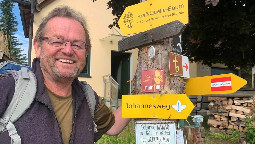 KAÖ-Präsident Ferdinand Kaineder steht bei Wegweisen auf einem Pilgernweg