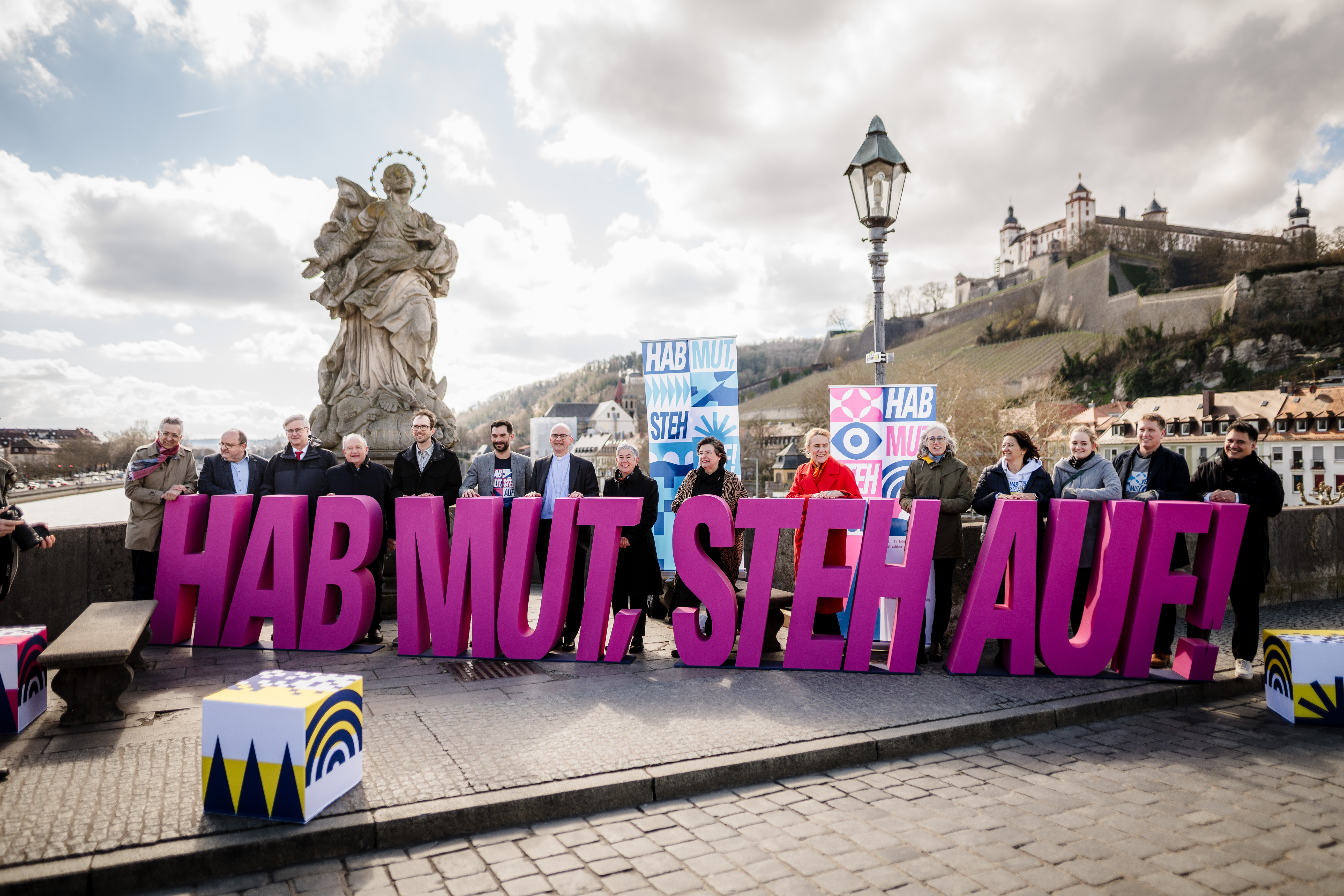 Eine Gruppe von Menschen hält die Buchstaben 'HAB MUT STEH AUF'