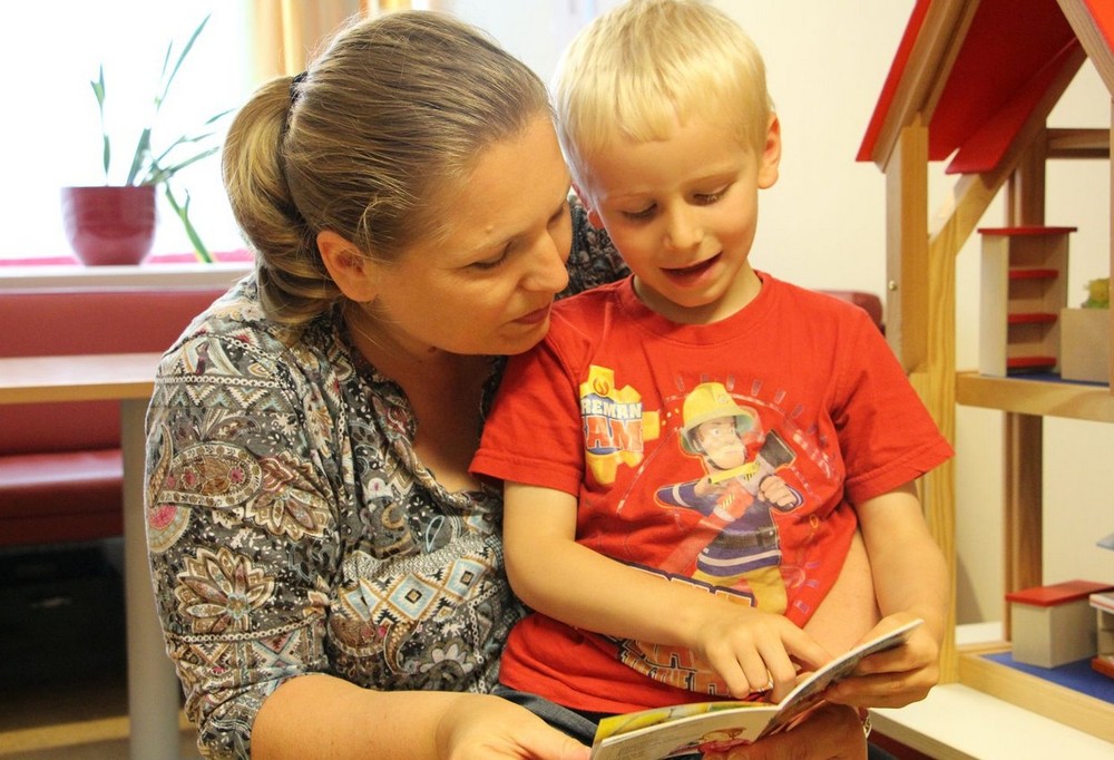 Mutter und Sohn lesen Buch / Caritas Socialis Mutter und Sohn lesen Buch
