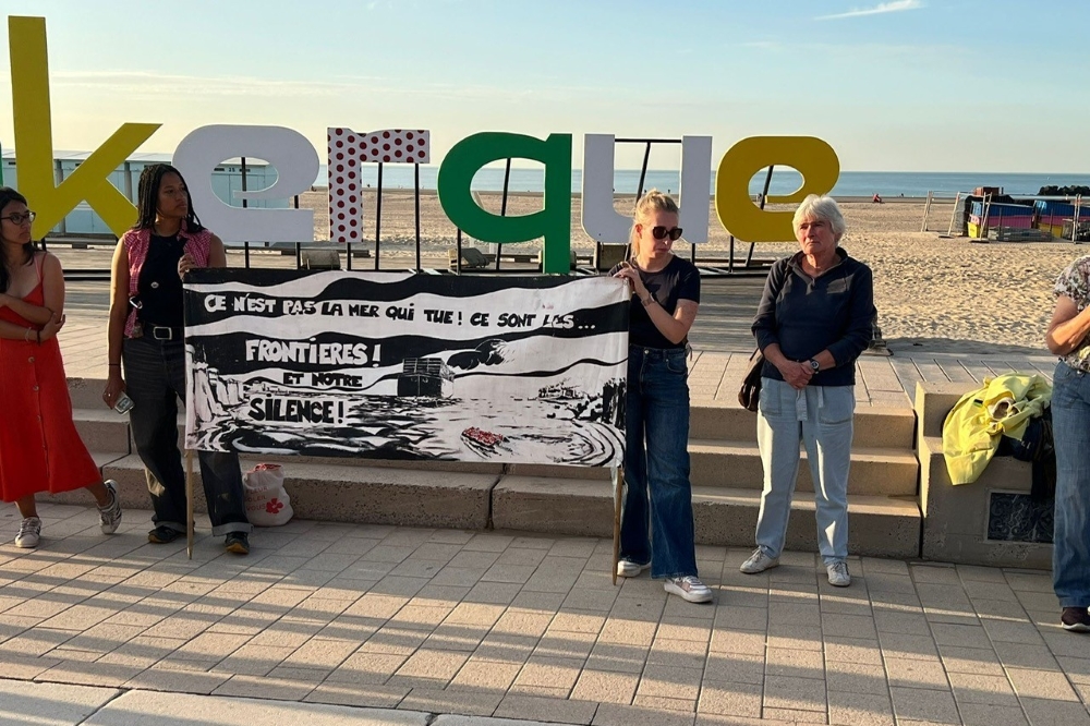 vier Frauen mit einem mit einem Banner demonstrieren an einer Küste