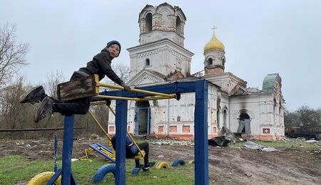 Kind spielt im ukrainischen Kriegsgebiet vor einer Kirche