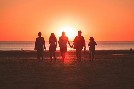 Gruppe von Menschen, die am Meer steht und in die untergehende Sonne blickt