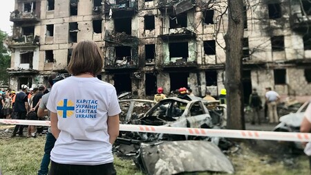 Caritas-Ukraine-Mitarbeiterin vor zerstörtem Wohnhaus in der Stadt Krywyj Rih