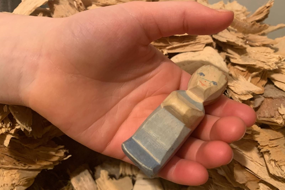 eine Holzfigur in der Hand 