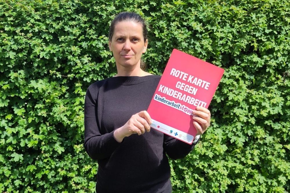 Bundesgeschäftsführerin der Katholischen Jungschar Österreich Sigrid Kickingereder hält in der Hand die rote Karte mit der Aufschrift Rote Karte gegen Kinderarbeit!