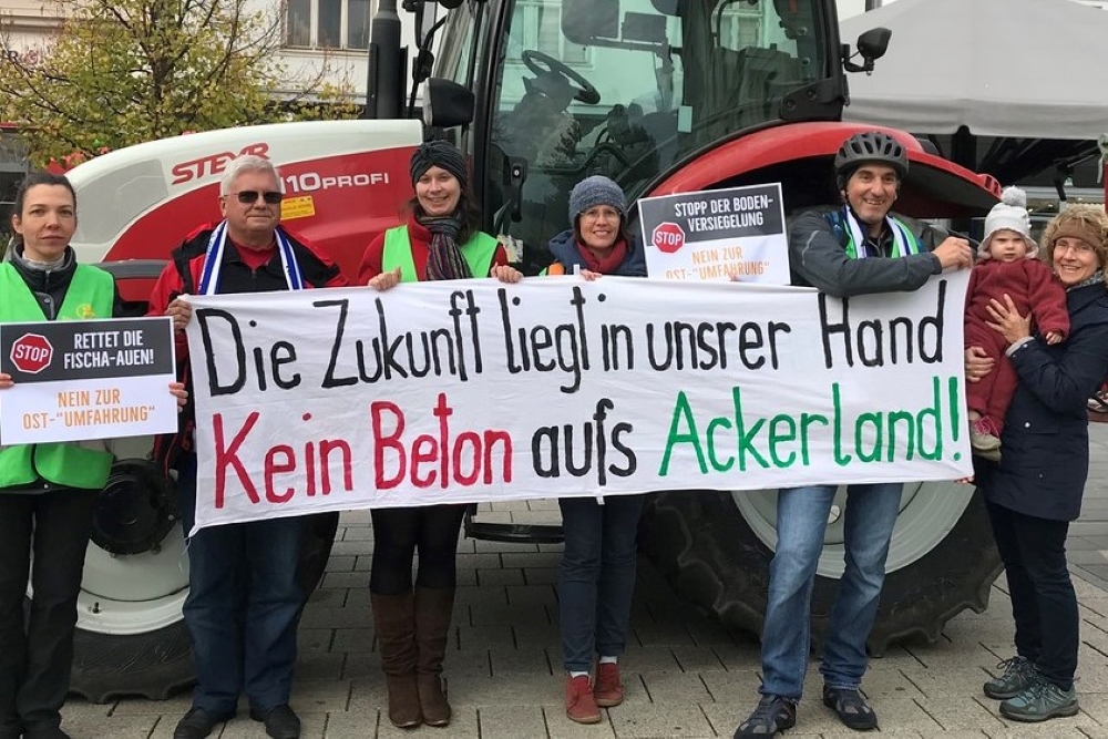 Vertreterinnen und Vertreter der Katholischen Aktion protestieren mit dem Plakat: Die Zukunft liegt in unsrer Hand. Kein Beton aufs Ackerland!