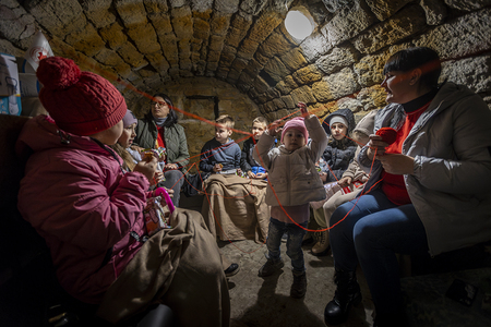 Die URCS Freiwillige Oleksandra Moroz (grüner Mantel mit den Kindern (v.l.): Tanja, Anja, Martin, Matiu Deruc (8), Denis Palii (8), Zlata, Sonja und Melania (jüngstes Mädchen). Freiwillige mit schwarzer Ponyfrisur: Olena Boiko (1982). Im Schutzkeller