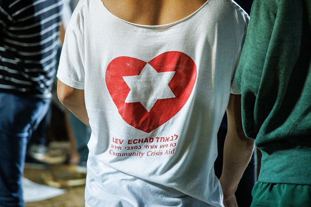 Freiwilliger Totengräber in Jerusalem / Copyright 2023, KNA GmbH, www.kna.de, All Rights Reserved, Andrea Krogmann Ein freiwilliger Totengräber trägt T-Shirt mit der Aufschrift 'Lev echad' (dt. ein Herz) und darüber ein Herz mit einem Davidstern, auf dem nationalen Militärfriedhof auf dem Herzlberg in Jerusalem (Israel) am 11. Oktober 2023.