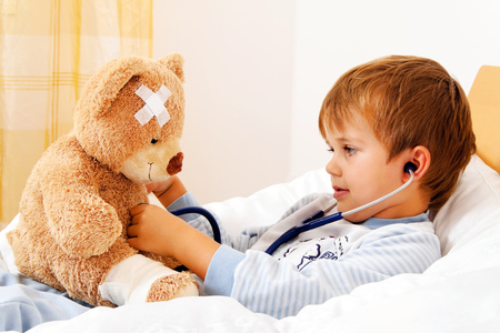 Krankes Kind untersucht Teddy mit Stethoskop / Erwin Wodicka Ein Krankes Kind untersucht Teddy mit Stethoskop