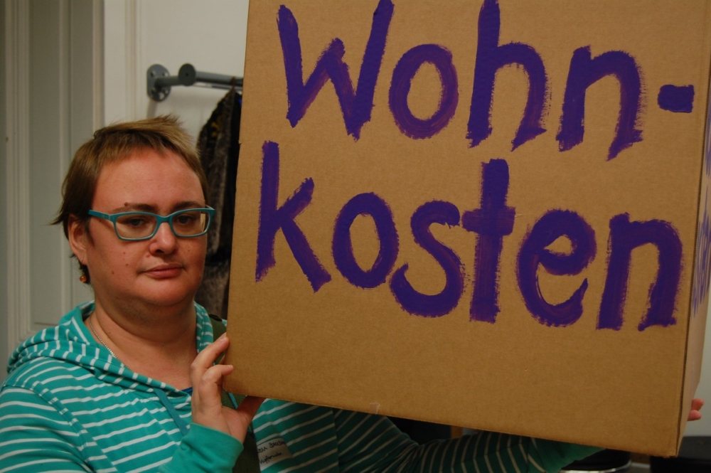 Eine Frau hält eine Kartonbox in den Händen mit der Aufschrift Wohnkosten